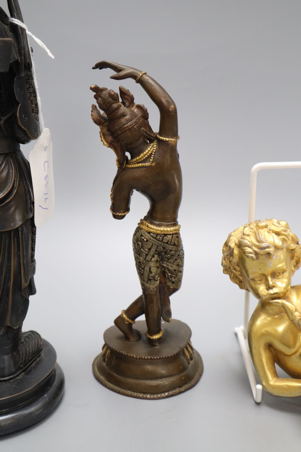 A gilt metal putti playing a musical conch shell, an Indian deity and a sage, tallest 26cm